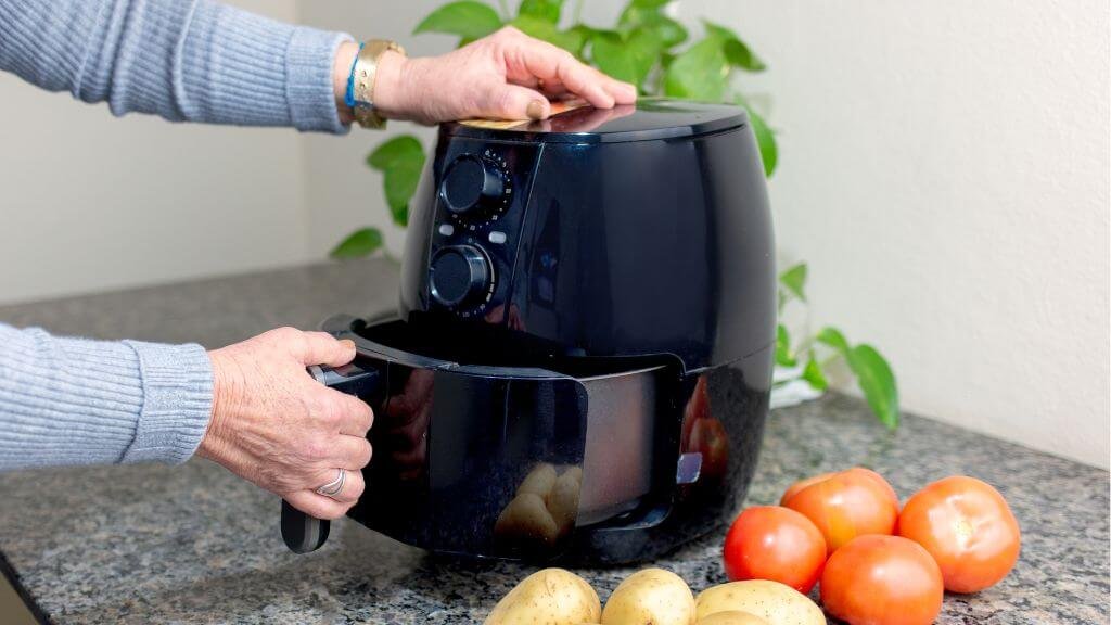 Persoon gebruikt airfryer in keuken – beste airfryer 2025 in gebruik
